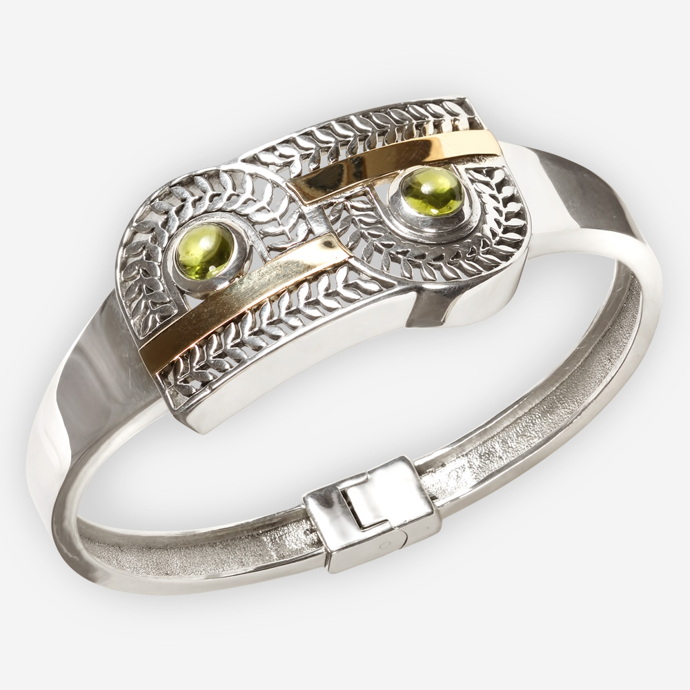Exotic silver cutout bangle is crafted from 925 sterling silver, 14k gold and feature a cutout leaf design and two gemstone cabochons.